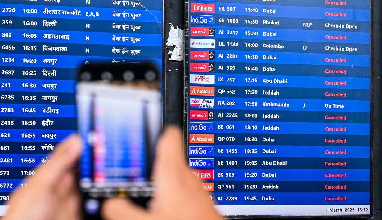 Ribuan penerbangan terpengaruh dan pusat-pusat penerbangan Timur Tengah yang sibuk, termasuk Dubai dan Doha, yang ditutup karena Iran bereaksi pasca serangan Amerika Serikat-Israel. Tampak dalam foto, seorang penumpang mengambil foto papan informasi penerbangan di Bandara Internasional Chhatrapati Shivaji Maharaj di Mumbai pada Minggu 1 Maret 2026 setelah dua maskapai penerbangan swasta terbesar India, IndiGo dan Air India, menangguhkan penerbangan ke semua tujuan di Timur Tengah. (Punit PARANJPE/AFP)