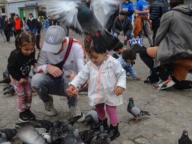 Wisatawan berkumpul sambil memberi makan dan bermain dengan burung merpati di Dam Square, Amsterdam, Belanda, Sabtu (26/5/2024). (merdeka.com/Arie Basuki)