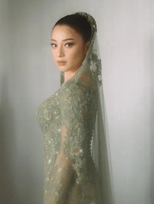 Pada momen lamarannya, Nikita Willy tampil anggun kenakan kebaya kurung berwarna hijau celadon rancangan Didiet Maulana. Kebaya berpayet ini dipadukan dengan veil warna senada dan songket padang. [@svarna_byikatindonesia].