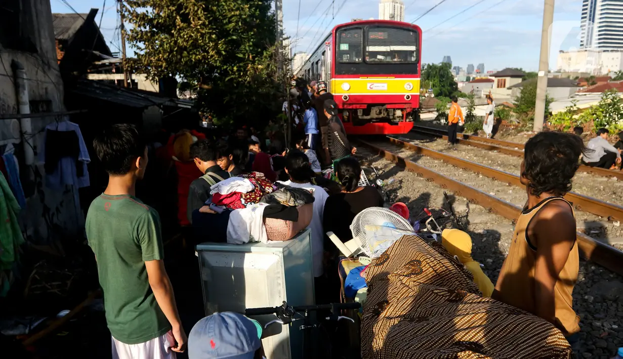 Kereta commuterline melintas dekat lokasi kebakaran di pemukiman padat penduduk kawasan Peninggaran Timur, Kebayoran Lama, Jakarta, Senin (27/1/2019). Kebakaran menewaskan satu orang pria akibat terjebak dalam kamar. (Liputan6.com/Johan Tallo)