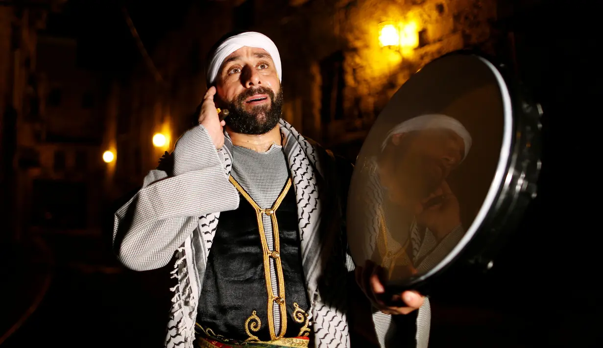 Michel Ayoub, seorang Kristen Arab-Israel, ketika membangunkan kaum muslim untuk melaksanakan sahur di Arce, Israel, Senin (20/6). Michel Ayoub sudah bertahun-tahun membangunkan sahur kaum muslim di sekitarnya selama Ramadan. (REUTERS/Ammar Awad)