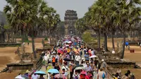 Turis mengunjungi candi Angkor Wat di provinsi Siem Reap, barat laut Kamboja pada 16 Maret 2019. Angkor Wat merupakan salah satu obyek wisata favorit dunia yang dibangun pada abad ke-12 Masehi. (TANG CHHIN Sothy / AFP)