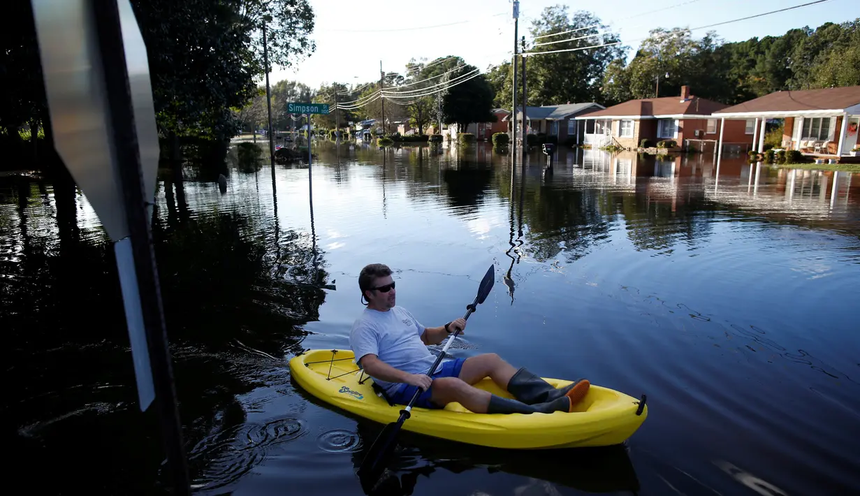 Parker Uzzell menggunakan kano untuk beraktivitas di tengah banjir yang merendam wilayah Lumberton di Carolina Utara, Amerika Serikat, 12 Oktober 2016. Banjir akibat badai Matthew tersebut merendam kota berpenduduk 21.000 orang itu. (REUTERS/Randall Hill)