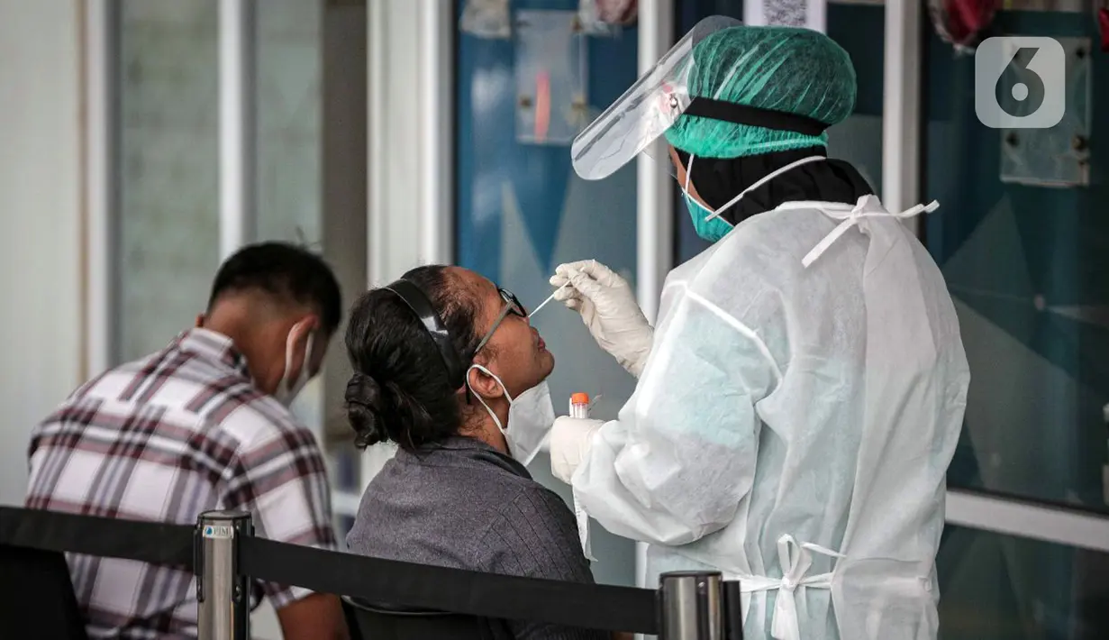 Petugas melakukan tes usap PCR kepada warga di Laboratorium Genomik Solidaritas Indonesia (GSI), Kamis (3/2/2022). Merebaknya varian Omicron membuat sejumlah lokasi tes COVID-19 ramai didatangi warga. (Liputan6.com/Faizal Fanani)
