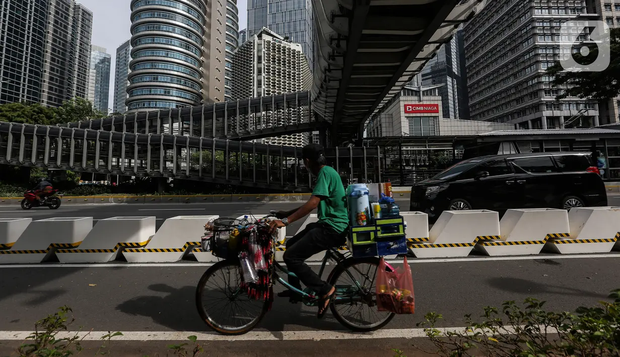 Seorang pedagang melintas di jalur sepeda permanen di jalan Sudirman, Jakarta, Rabu (24/2/2021). Pemprov DKI Jakarta mulai mempermanenkan jalur sepeda di Jalan Sudirman - Thamrin, Jakarta Pusat. (Liputan6.com/Johan Tallo)
