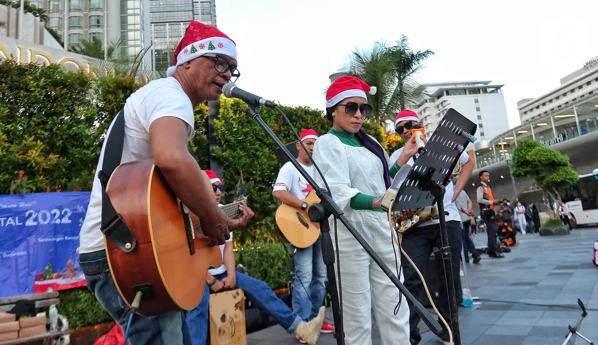 Musisi mengelar pertunjukan musik bernuansa Natal di jalur Pedestrian Bundaran HI, Jakarta Pusat, Selasa (20/12/2022). Pergelaran musik bernuansa Natal tersebut sebagai bentuk pertunjukan untuk menghibur warga yang melintas di Kawasan itu. (Liputan6.com/Angga Yuniar)