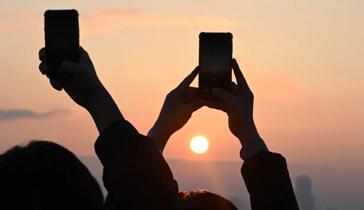 Menyaksikan detik-detik matahari terbenam atau sunset terakhir di tahun 2023 menjadi keasyikan tersendiri bagi sebagian warga. (Jung Yeon-je / AFP)