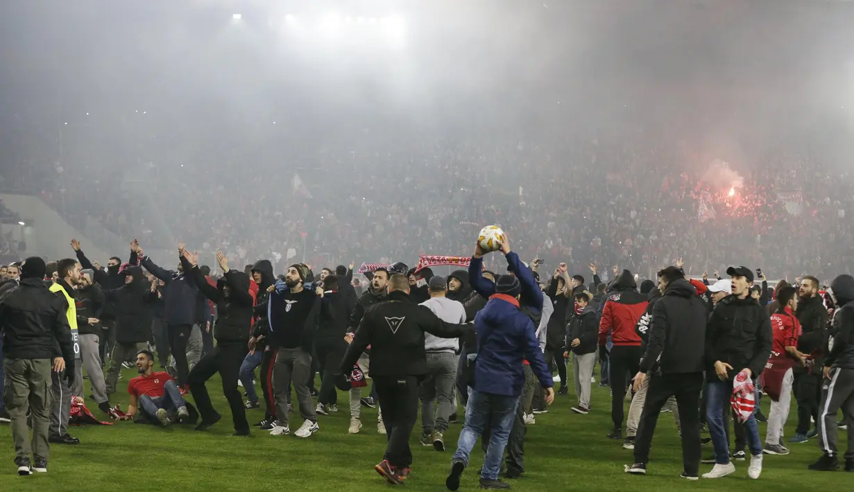 Para suporter Olympiakos turun ke lapangan merayakan kemenangan atas AC Milan pada laga Europa di Stadion Georgios Karaiskakis, Athena, Kamis (13/12). Olympiakos menang 3-1 atas AC Milan. (AP/Thanassis Stavrakis)
