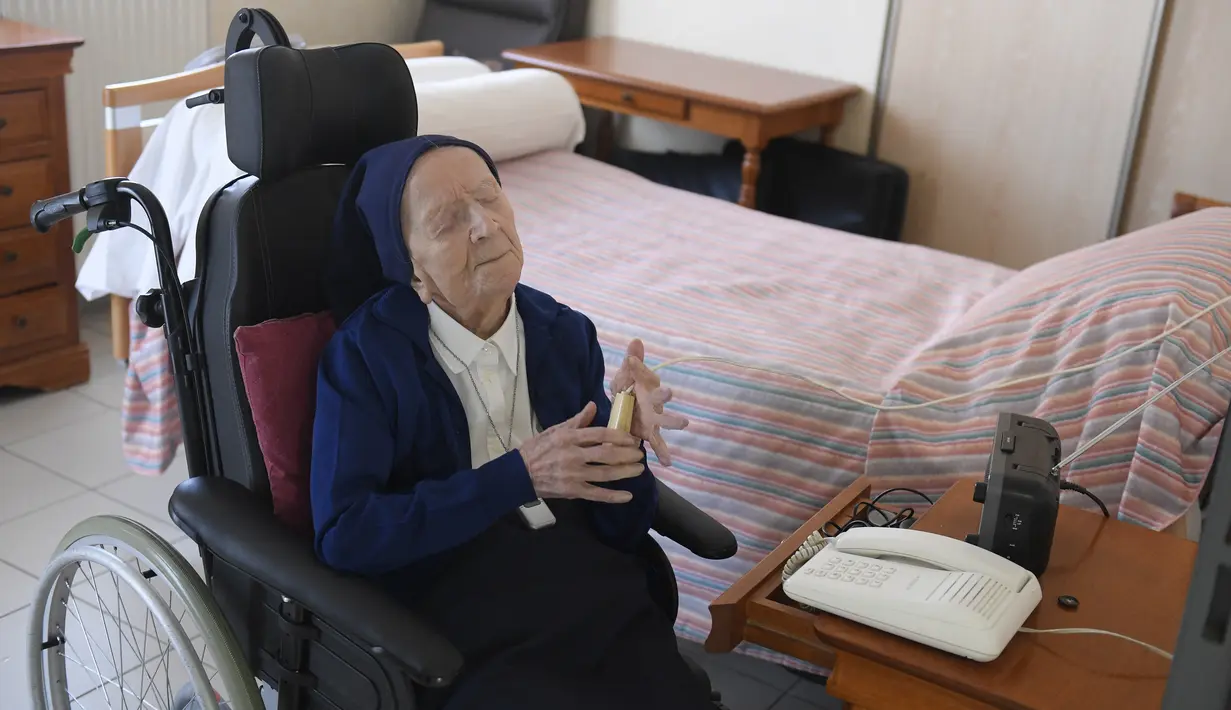 Lucile Randon atau Suster Andre, warga negara Prancis dan orang tertua di Eropa, berdoa di atas kursi roda, di Toulon, Rabu (10/2/2021). Sister Andre, yang mengalami kebutaan dan menggunakan kursi roda, kini tengah menanti hari ulang tahunnya yang ke-117 pada 11 Februari. (NICOLAS TUCAT/AFP)