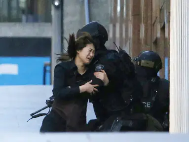 Seorang sandera berlari ke arah polisi setelah berhasil keluar dari Kafe Lindt, Martin Place, Sydney, Senin (15/12/2014). (REUTERS/Jason Reed)