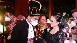 Dalam acara itu, Yuni Shara tampil anggun dengan kebaya hitam dari brokat lengkap dengan sanggul besar. Lipstik merah menyala membuat riasannya makin paripurna. Berbincang dengan Gibran yang berkemeja putih dilapisi beskap, belangkon, dan setagen merah, Yuni Shara tampak membahas sesuatu sambil memegang lengan Sang Wali Kota. (Foto: Dok. Instagram @yunishara36)