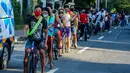 Para pengendara sepeda mengantre untuk mendapatkan helm dan selempang reflektif gratis yang dibagikan oleh sejumlah anggota lembaga swadaya masyarakat di Manila, Filipina (9/7/2020). (Xinhua/Rouelle Umali)