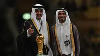 Sheikh Jassim Bin Hamad Al-Thani (kanan) bersama saudaranya Sheikh Tamim bin Hamad al-Thani dari Qatar) berpose di atas panggung dengan trofi Piala Dunia pada akhir pertandingan final Piala Dunia Qatar 2022 antara Argentina dan Prancis di Stadion Lusail di Lusail, utara Doha pada 18 Desember 2022. (AFP/Paul Ellis)