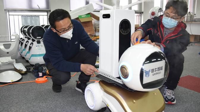 Para teknisi menyetel robot desinfeksi generasi kedua di sebuah perusahaan teknologi di Qingdao, Provinsi Shandong, China, 11 Februari 2020. Beberapa robot desinfeksi ini telah digunakan di ruang isolasi sejumlah rumah sakit di China. (Xinhua/Li Ziheng)