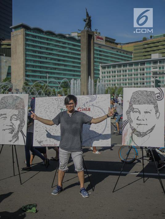 Seorang pria berpose di depan lukisan capres 01 dan 02  yang bertema ‘ Pemilu Penuh Cinta’  saat Car Free day di kawasan Bundaran HI, Jakarta, MInggu (14/4). Kampanye tersebut untuk mengajak masyarakat untuk berpartisipasi dalam Pemilu secara Damai. (Liputan6.com/Faizal Fanani)