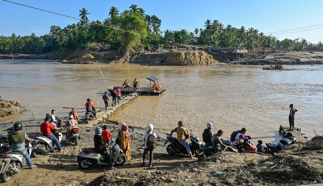 Sejumlah warga menunggu waktu naik rakit tali untuk menyeberangi Sungai Peusangan menyusul banjir bandang yang menghancurkan desa-desa di sekitarnya di Kabupaten Bireuen, provinsi Aceh, pada Senin 5 Januari 2026. Sebulan lebih pasca terjangan banjir bandang, warga di sekitar Sungai Peusangan Bireuen Aceh masih menggunakan metode penyeberangan darurat. (CHAIDEER MAHYUDDIN/AFP)