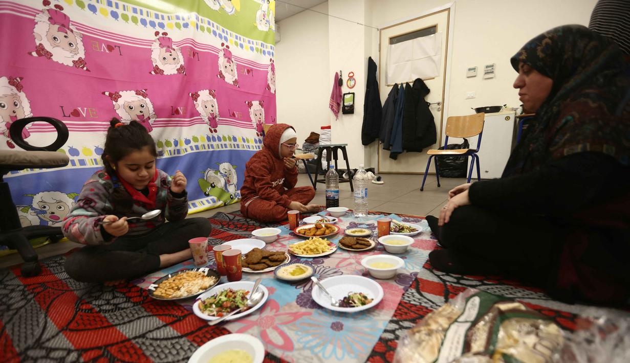 Seorang perempuan pengungsi yang tinggal bersama keluarganya di ruang kelas sekolah, setelah melarikan diri dari serangan udara Israel di pinggiran selatan Beirut, Lebanon, duduk untuk berbuka puasa bersama, pada 7 Maret 2026. Momen berbuka puasa Ramadan 1447 Hijriah di Beirut, Lebanon, berlangsung dalam situasi penuh keprihatinan. (Ibrahim AMRO/AFP)