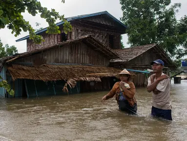 Dua warga melintasi banjir yang merendam di kecamatan Mawlamyine, negara bagian Mon, Myanmar (18/6). Hujan deras mengakibatkan banjir rendam rumah warga dan tanah longsor. (AFP PHOTO / Ye Aung Thu)
