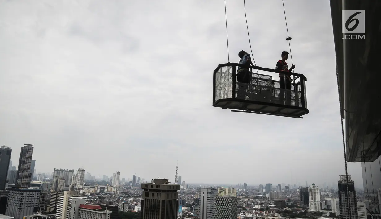 Pekerja naik gondola tanpa helm keselamatan beraktivitas di gedung bertingkat di Jakarta, Rabu (15/11). Banyak kejadian kecelakaan kerja di ketinggian disebabkan karena mahalnya peralatan pengaman pribadi yang ada di pasaran. (Liputan6.com/Faizal Fanani)