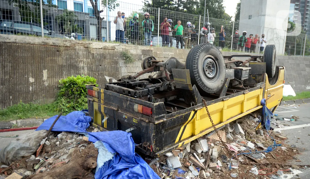 Truk bermuatan puing terbalik akibat salah satu ban belakang lepas di jalan tol Pondok Indah dekat pintu keluar Lebak Bulus, Jakarta, Jumat (29/5/2020). Dalam kecelakaan tersebut tidak ada korban jiwa namun membuat kendaraan yang melintas jalan tol tersendat. (merdeka.com/Dwi Narwoko)