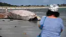 Orang-orang melihat bangkai paus sirip di pantai di Penmarc'h, Prancis barat pada Selasa (13/8/2019). Paus sepanjang 13 meter yang terdampar setelah mati di laut tersebut merupakan mamalia terbesar kedua di dunia. (Photo by Fred TANNEAU / AFP)