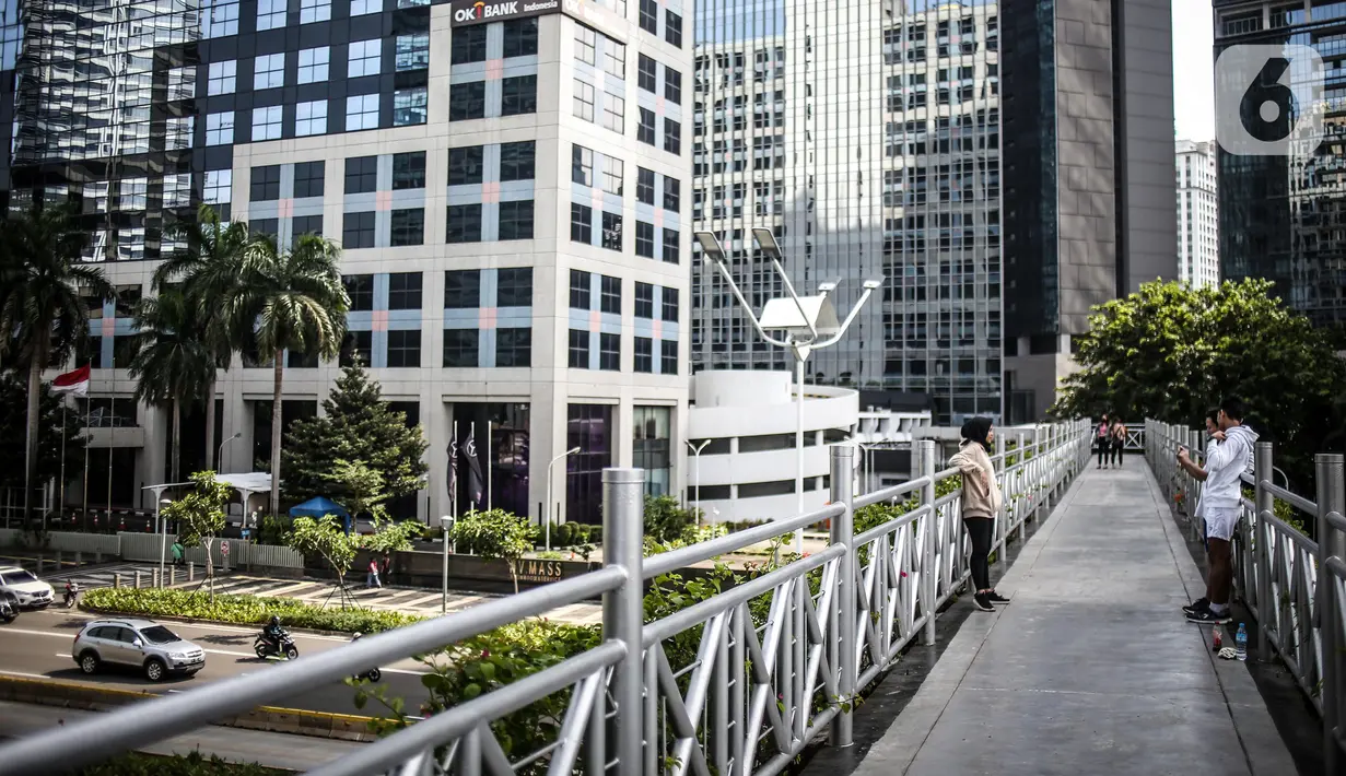 Warga berfoto di jembatan penyeberangan orang (JPO) kawasan Sudirman, Jakarta, Kamis (4/6/2020). Gubernur DKI Jakarta Anies Baswedan mengatakan dengan perpanjangan Pembatasan Sosial Berskala Besar (PSBB) Jakarta akan memasuki fase transisi selama bulan Juni. (Liputan6.com/Faizal Fanani)