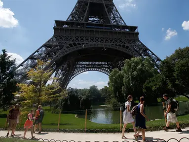 Turis berjalan melewati Menara Eiffel di Paris, Kamis (2/8). Wisatawan harus menelan kekecewaan karena mereka tak bisa masuk ke lokasi wisata yang menjadi ikon Prancis itu. (AP Photo/Michel Euler)