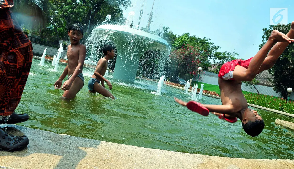 Seorang anak melompat di bundaran air mancur Jalan Teuku Umar, Jakarta Pusat, Sabtu (23/9). Cuaca panas ibu kota memaksa anak-anak menceburkan diri di kolam untuk menyejukkan badan. (Liputan6.com/Helmi Afandi)