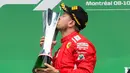 Pembalap Ferrari, Sebastian Vettel mencium piala penghargaan usai menjuarai F1 GP di Montreal, Kanada, Minggu (10/6). Performa impresif pembalap asal Jerman itu sulit dibendung para rivalnya. (Ryan Remiorz/The Canadian Press via AP)