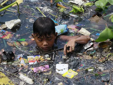 Seorang Anak laki-laki memilah sampah yang terapung untuk di jadikan bahan daur ulang di sebuah sungai yang tercemar di kota navotas, Manila, Kamis (2/7/2015). Daur ulang bertujuan untuk mengurangi tingkat pencemaran sungai. (REUTERS/Romeo Ranoco)