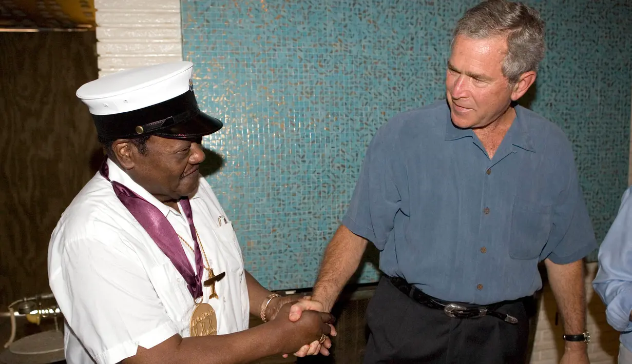 Foto yang diambil pada 29 Agustus 2006 menunjukkan musisi Fats Domino (kiri) mengenakan mendali bersalaman dengan Presiden AS saat itu, George W. Bush. Setelah berita kepergian Fats Domino beredar, musisi dunia pun ikut berduka. (AFP Photo/Eric Daper)