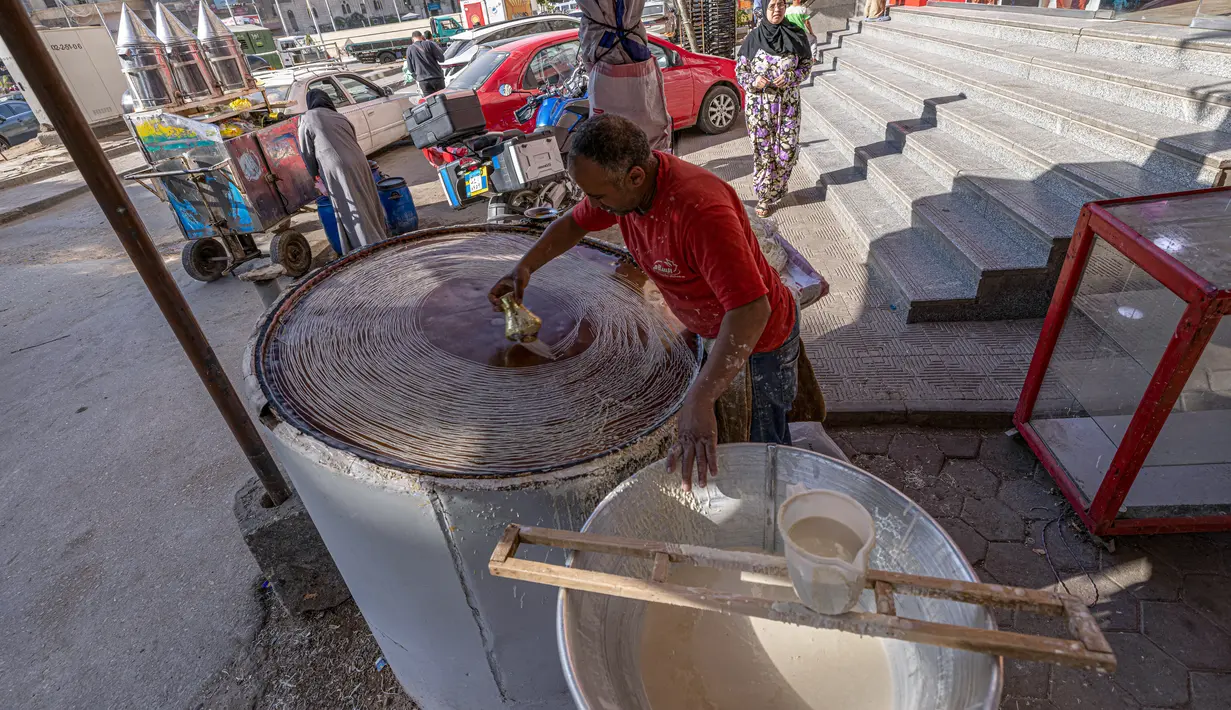Pembuat penganan Mesir Mostafa Anwar membuat makanan penutup tradisional yang disebut "Kunafa" pada bulan Ramadhan, di kiosnya di ibu kota Kairo, 14 April 2022.  Kunafa terbuat dari adonan pastry mirip bihun, kemudian diisi dengan isian kacang, lalu dipanggang. (Khaled DESOUKI/AFP)