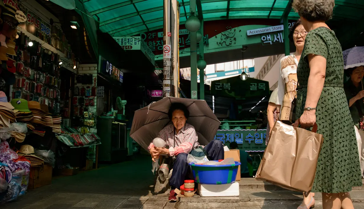 Seorang wanita tua duduk di sebuah jalan di pasar Namdaemun di Seoul (2/7/2019). Tiap hari Pasar Namdaemun buka pada pukul 11.00 pagi dan tutup pada pukul 03.00 pagi pada hari berikutnya. (AFP Photo/Minji Suh)