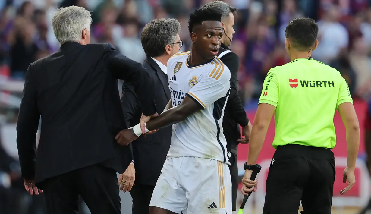 Beruntung, Vinicius tidak diganjar kartu apa pun karena aksinya yang terkesan mengulur waktu tersebut. Pada akhirnya, Real Madrid mengunci kemenangan 2-1 atas Barcelona. (AFP/Lluis Gene)