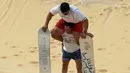 Pengunjung menggendong temannya setelah berseluncur di gurun pasir Wadi el-Rayan Fayoum, Mesir (18/11). Di gurun ini menyajikan banyak hiburan dan pariwisata salah satunya, berseluncur di pasir atau sandboarding. (Reuters/Mohamed Abd El Ghany)