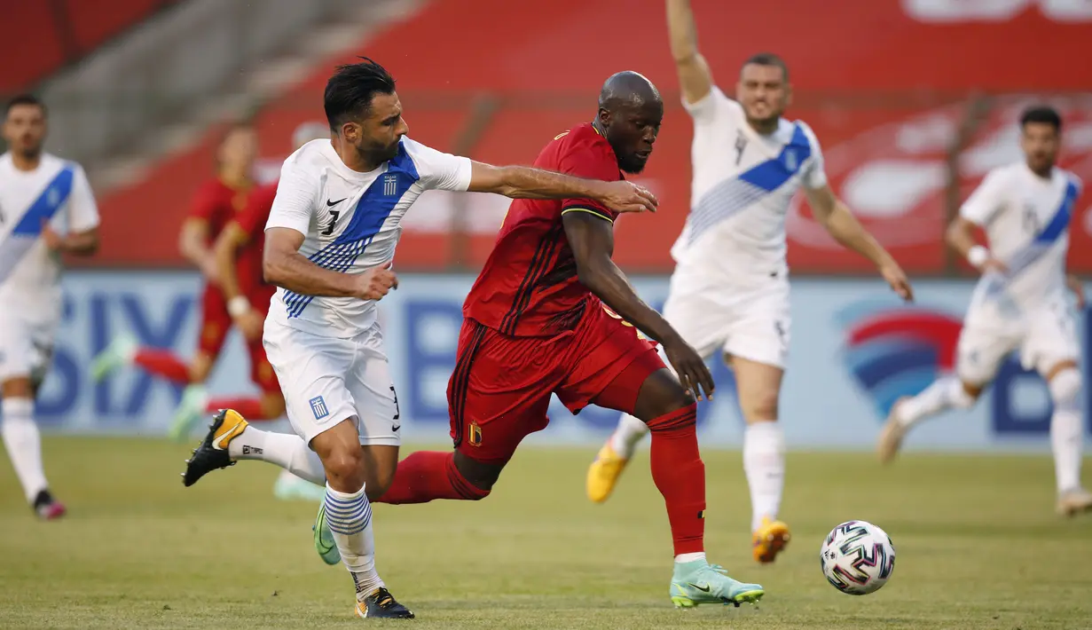 Striker Belgia, Romelu Lukaku, berebut bola dengan pemain Yunani, Giorgos Tzavellas, pada laga uji coba di Stadion King Baudouin, Jumat (4/6/2021). Kedua tim bermain imbang 1-1. (AP/Francisco Seco)