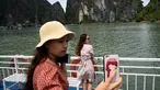 Wisatawan domestik berpose untuk foto di atas kapal di tengah Ha Long Bay, Quang Ninh, Vietnam, (16/5/2020). Sempat terpukul akibat pandemi virus corona Covid-19, pariwisata Vietnam kembali menggeliat setelah otoritas setempat melonggarkan pembatasan perjalanan. (AFP/Manan Vatsyayana)