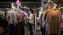 Seorang wanita memeriksa pakaian untuk dijual di pasar malam, Wuhan, Provinsi Hubei, China, 3 Agustus 2020. Wuhan kembali pulih sejak karantina terkait COVID-19 dicabut. (Hector Retamal/AFP)
