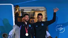Kapten Argentina Lionel Messi (kiri) memegang Trofi Piala Dunia 2022 bersama pelatih Lionel Scaloni saat turun dari pesawat setibanya di Bandara Internasional di Ezeiza, provinsi Buenos Aires, Argentina (20/12/2022). Argentina tampil sebagai juara Piala Dunia 2022 setelah menumpas Prancis melalui adu penalti di final. (AFP/Luis Robayo)
