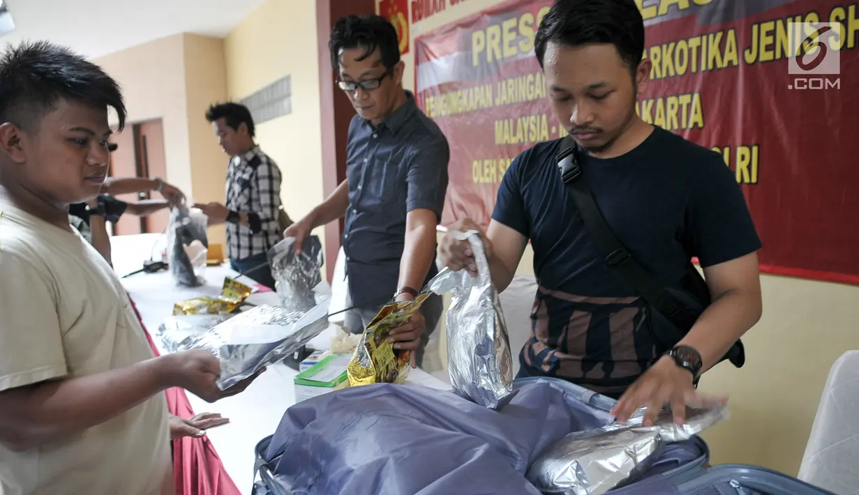 Petugas membongkar barang bukti kasus peredaran narkotika jenis sabu jaringan Malaysia dalam jumpa pers di Rumah Sakit Polri, Selasa (13/6). Modus operandi dalam mengedarkan narkoba ini dengan dikamuflase di dalam koper. (Liputan6.com/Yoppy Renato)