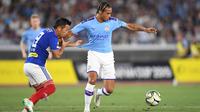 Gelandang Yokohama Marinos, Takuya Kida, berebut bola dengan gelandang Manchester City, Leroy Sane, pada laga pramusim di Stadion Yokohama, Jepang, Sabtu (27/7). Yokohama kalah 1-3 dari City. (AFP/Charly Triballeau)