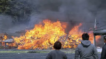 Penduduk setempat berdiri dekat lokasi kebakaran yang terkena dampak kebakaran hutan di daerah Gangneung, Korea Selatan, Selasa (11/4/2023). Ratusan warga Korea Selatan terpaksa mengungsi dari kebakaran hutan akibat angin kencang yang membakar sebagian kota pesisir timur itu dan menghancurkan puluhan rumah. (You Hyung-jae/Yonhap via AP)