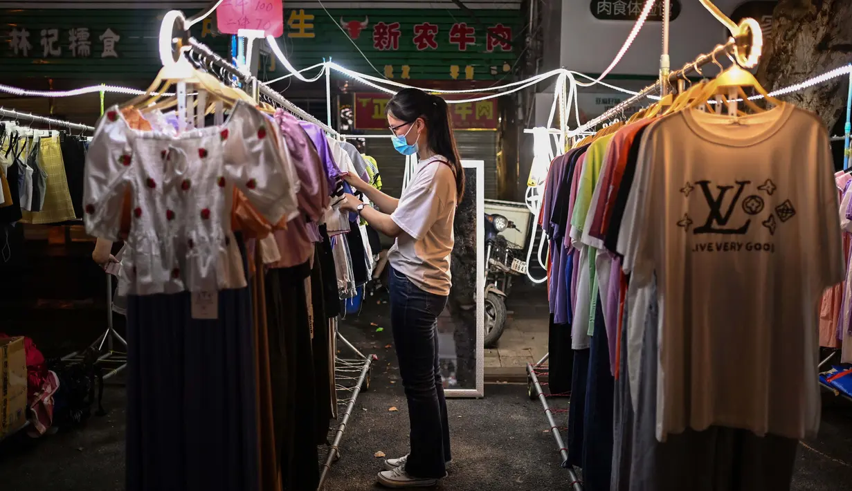 Seorang wanita memeriksa pakaian untuk dijual di pasar malam, Wuhan, Provinsi Hubei, China, 3 Agustus 2020. Wuhan kembali pulih sejak karantina terkait COVID-19 dicabut. (Hector Retamal/AFP)