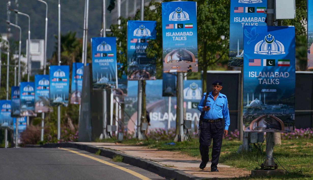 Seorang petugas polisi berjalan melewati papan reklame di dekat Hotel Serena menjelang putaran kedua negosiasi antara Amerika Serikat dan Iran, di Islamabad, Pakistan, Selasa 21 April 2026. Pemerintah Pakistan saat ini tengah meningkatkan penjagaan keamanan di wilayah Islamabad secara besar-besaran. (AP Photo/Anjum Naveed)