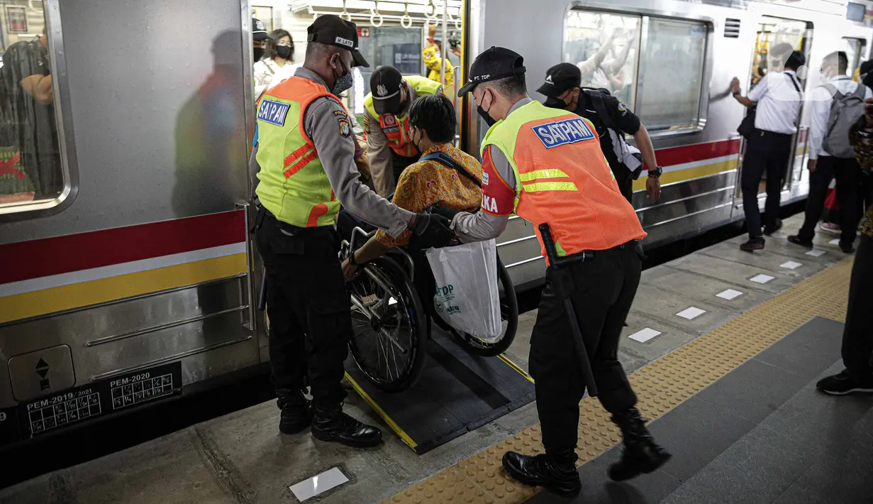Petugas membantu penyandang disabilitas naik ke kereta saat menjajal fasilitas di Stasiun Jatinegara, Jakarta, Jumat (3/12/2021). KAI Commuter mengajak pengguna transportasi dengan disabilitas untuk merasakan sarana dan prasarana perkeretaapian yang lebih aksesibel. (Liputan6.com/Faizal Fanani)