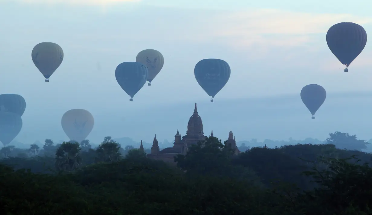 Sejumlah balon udara terbang di atas kuil tua selama matahari terbit di Bagan, distrik Nyaung U, Myanmar tengah (16/12). Selain balon udara, banyak wisatawan datang ke Bagan karena ingin melihat pagoda, stupa, dan warisan kuno. (AP Photo/Aung Shine Oo)
