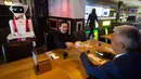 Pemilik restoran, Shu Lei Hu (kiri) dan suaminya Shao Song Hu menunjukkan penggunaan robot pengganti pelayan di restoran keluarga Royal Palace, Belanda, 27 Mei 2020. Satu hal yang pasti akan dilakukan robot berwarna merah-putih ini adalah memastikan aturan jarak sosial dihormati. (AP/Peter Dejong)