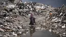 Diketahui, sebagian besar warga masih menempati tenda-tenda dan tempat penampungan sementara lainnya setelah perang antara Israel dan Hamas sejak Oktober 2023 silam. Tampak dalam foto, warga Palestina berjalan melewati reruntuhan di tengah cuaca buruk Kota Gaza, Kamis 11 Desember 2025. (AP Photo/Jehad Alshrafi)