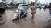 Seorang pengendara memperbaiki motornya yang mogok saat melintasi banjir di Jalan Boulevard Barat Raya, Kelapa Gading, Jakarta, Kamis (15/2). Hujan lebat yang mengguyur Jakarta mengakibatkan sejumlah wilayah terendam banjir. (Liputan6.com/Arya Manggala)
