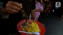 Warga menunjukkan menu makan siang di warung nasi kuning Podjok Halal yang berada di Vihara Kim Tek Ie, Petak Sembilan, Jakarta, Selasa (24/12/2019). Makanan yang ada di warung ini dipesan melalui warteg-warteg sekitar vihara. (merdeka.com/Imam Buhori)